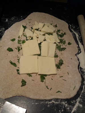 Fresh herbs and slices of butter leaving room to fold over the dough.
